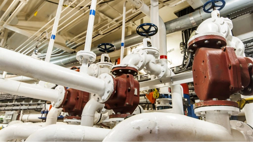 Complex network of insulated piping and manual valves in an industrial facility, likely used for controlling the flow of various fluids in processes such as energy, chemical, or utility services.